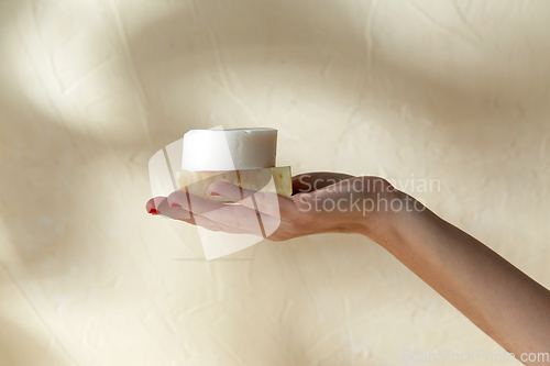 Image of hand holding bar of craft soap on beige background