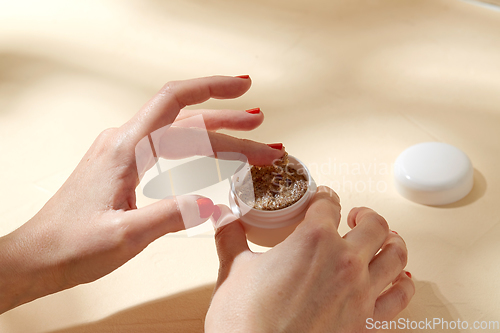 Image of close up of hands with natural body scrub in jar