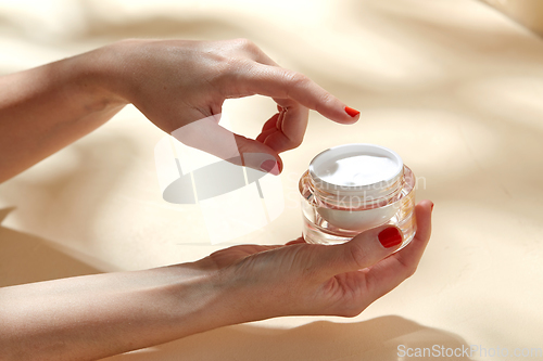 Image of female hand holding jar of moisturizer