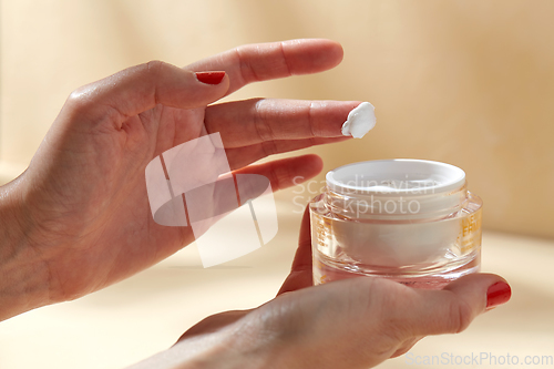 Image of female hand holding jar of moisturizer