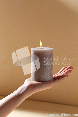 Image of hand holding burning aroma candle on palm