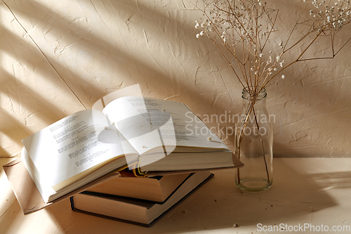 Image of books and decorative dried flowers in glass bottle