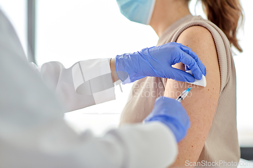 Image of female doctor with syringe vaccinating patient