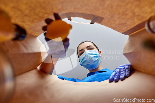 Image of woman in gloves and mask with food in paper bag