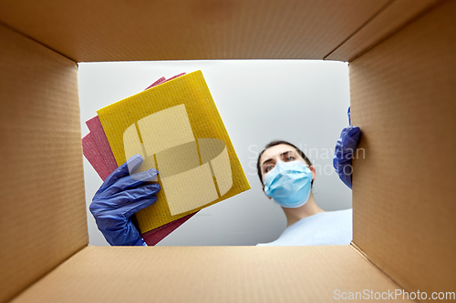 Image of woman in mask taking cleaning supplies from box