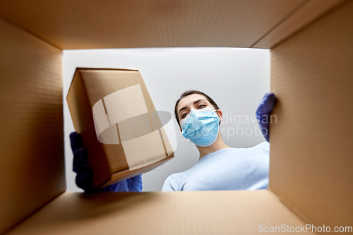 Image of woman in mask taking box from parcel