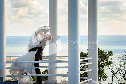 Image of The newlyweds kiss in a beautiful picturesque gazebo against the backdrop of the sea