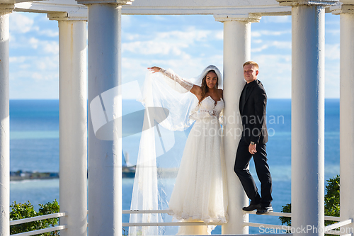 Image of Newlyweds in a beautiful gazebo stand on a metal railing