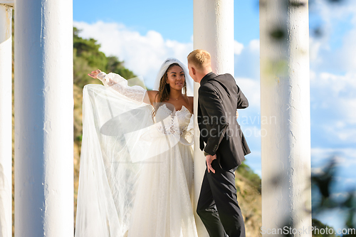 Image of Newlyweds in a beautiful gazebo with columns against the backdrop of mountains and sky