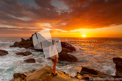 Image of Woman watches rich red sunrise over the ocean