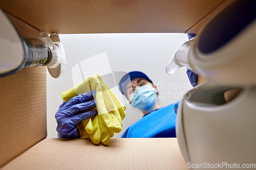 Image of woman in mask packing cleaning supplies in box