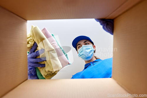 Image of woman in mask packing clothes to parcel box