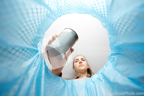Image of woman throwing tin can into rubbish bin