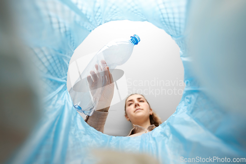 Image of woman throwing plastic bottle into trash can