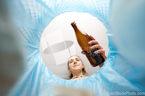 Image of woman throwing glass bottle into trash can