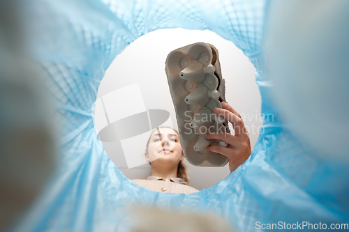 Image of woman throwing egg box into trash can