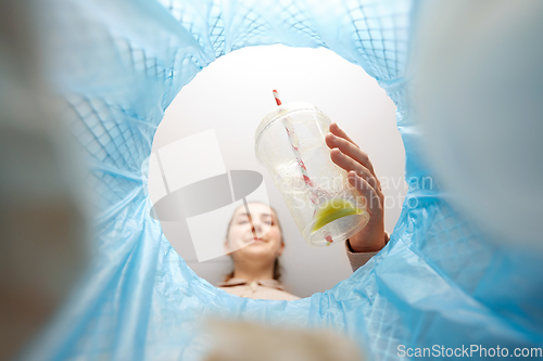 Image of woman throwing plastic cup into trash can