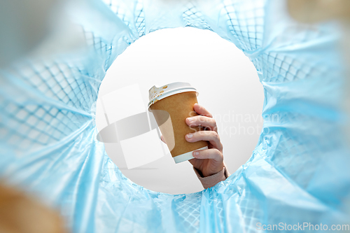 Image of hand throwing coffee cup into trash can