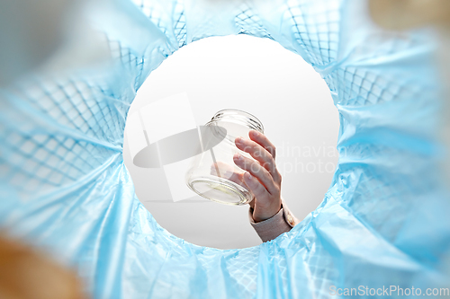 Image of hand throwing glass jar into trash can