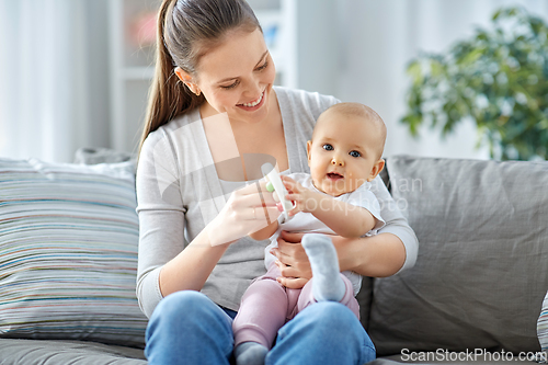 Image of mother and little baby playing with rattle at home