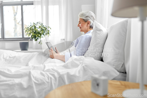 Image of senior woman with tablet pc in bed at home bedroom