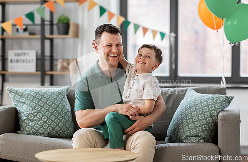 Image of happy father and little son at home birthday party