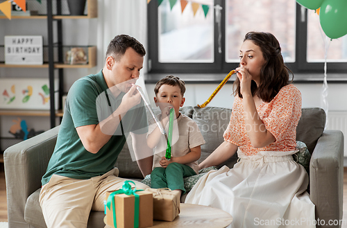 Image of happy family with gifts and party blowers at home