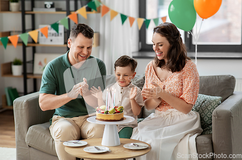 Image of happy family with birthday cake at home