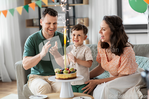 Image of happy family with birthday cake at home