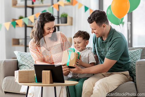 Image of happy family giving present to little son at home