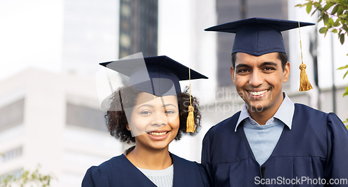 Image of happy students or bachelors in mortar boards