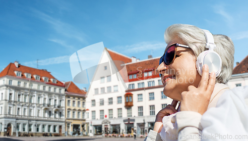 Image of old woman in headphones listens to music outdoors