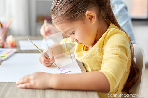 Image of little girl drawing picture with colors and brush
