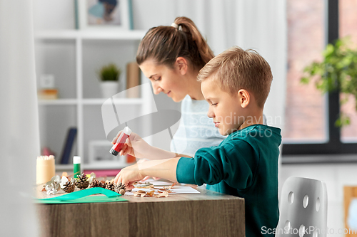 Image of mother and son making pictures of autumn leaves
