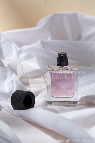 Image of bottle of perfume and cap on white sheet