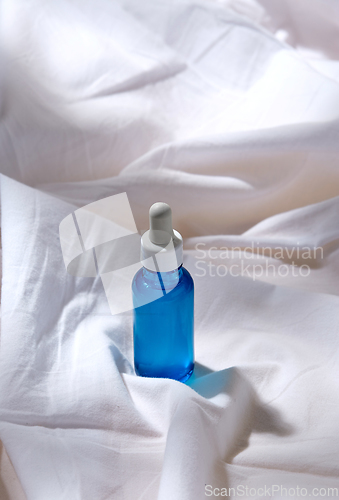 Image of bottle of serum on white sheet