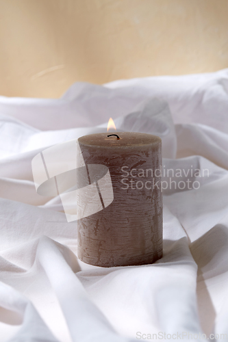 Image of burning aroma candle on white sheet