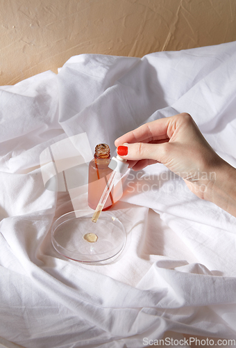 Image of female hand with dropper applying serum to glass