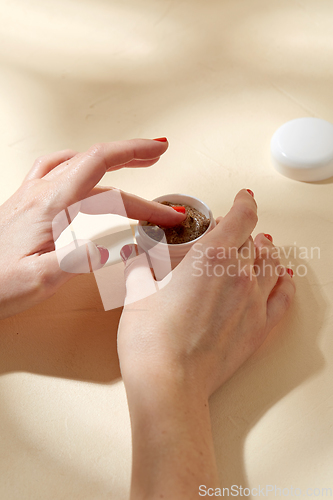 Image of close up of hands with natural body scrub in jar