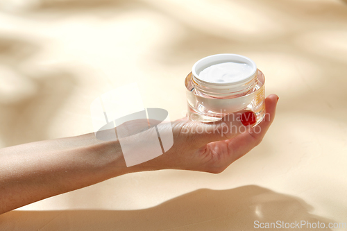 Image of female hand holding jar of moisturizer