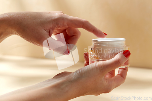 Image of female hand holding jar of moisturizer