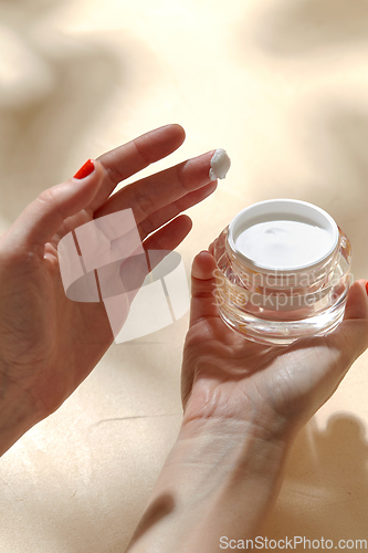 Image of female hand holding jar of moisturizer