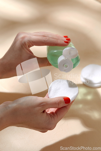 Image of close up of hands applying lotion to cotton pad