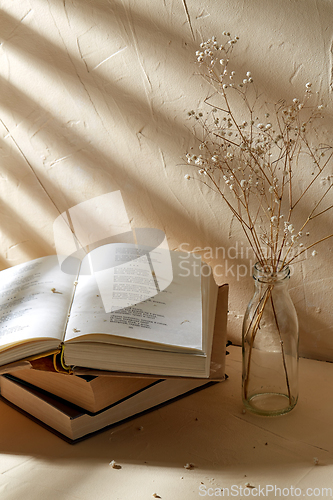 Image of books and decorative dried flowers in glass bottle