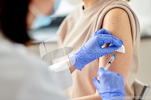 Image of female doctor with syringe vaccinating patient