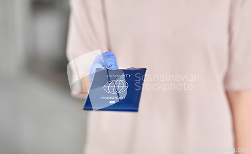 Image of woman in glove holding immunity passport