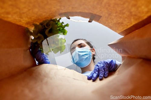 Image of woman in gloves and mask with food in paper bag