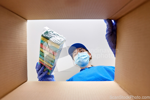 Image of woman in mask packing kitchen sponges to box