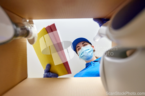 Image of woman in mask packing cleaning supplies in box