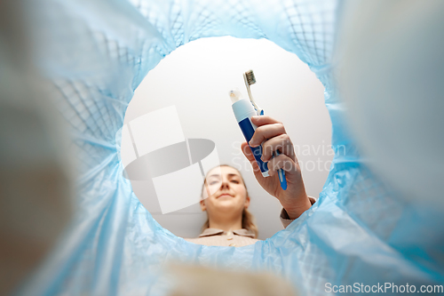 Image of woman throwing toothbrush into trash can